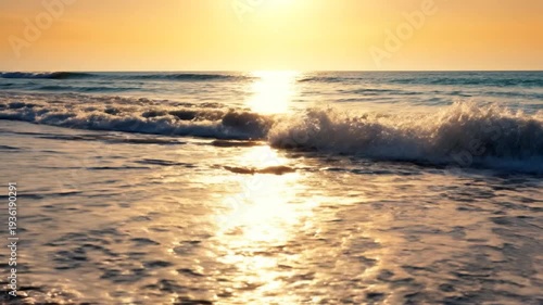 Golden sunset light reflects on ocean waves washing onto a sandy beach