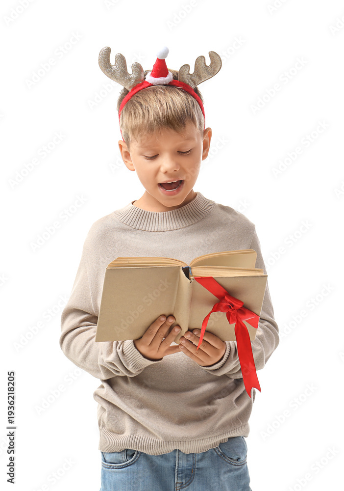 Fototapeta premium Cute little boy in Christmas reindeer horns reading book on white background