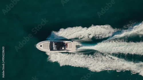 Aerial top-down drone view of a speedboat cruising across deep blue ocean water in Miami, Florida leaving a white wake trail.