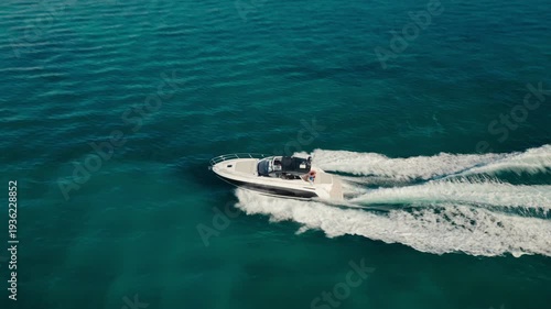 Aerial drone view of a luxury boat cruising across a calm ocean in Miami, Florida leaving a white wake trail.