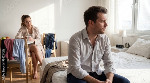 Silent Discord: A couple sits in a bedroom, distance between them, each lost in thought, an unspoken tension hangs in the air. This image portrays the unspoken story of separation.