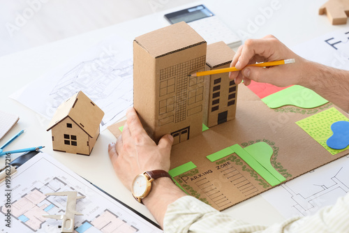 Male hands working on 3D zoning plan at table in office, closeup