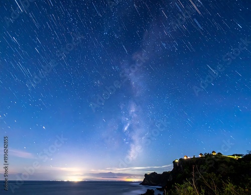 Wallpaper Mural Long exposure shot reveals the Milky Way and star trails over a coastal cliff at dusk, showing ocean and distant lights Torontodigital.ca