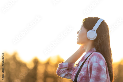 Obraz na płótnie A beautiful Chinese woman listening to music in golden rice paddies in autumn
