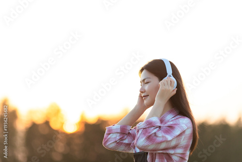 Foto A beautiful Chinese woman listening to music in golden rice paddies in autumn
