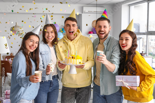 Group of young friends with cake and gift celebrating Birthday at party