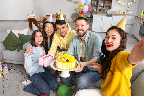 Group of young friends with cake taking selfie at Birthday party