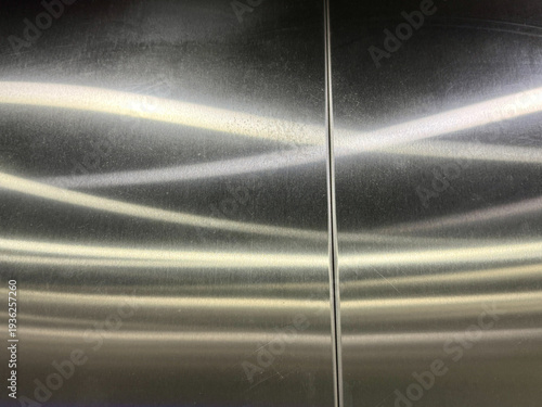 The image is of a silver metal surface with a shiny, reflective quality