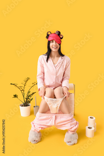 Young woman in pajamas sitt...