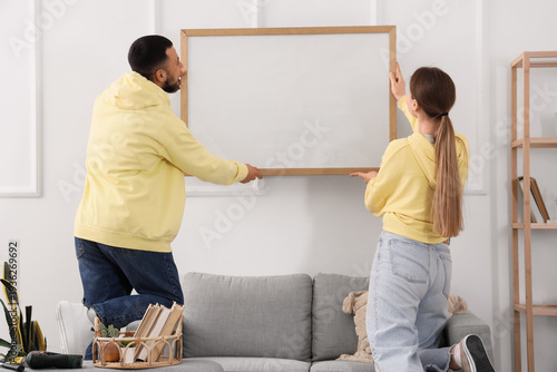 Young couple hanging blank ...
