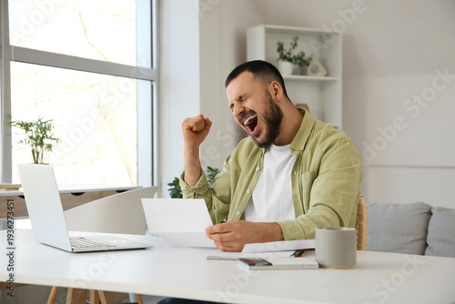 Photos Happy young man with refund form at table in room