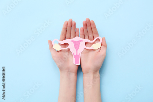Woman holding paper uterus on blue background