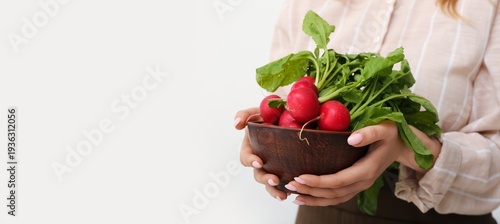 Woman holding bowl of ripe radish on light background with space for text, closeup