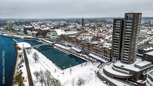 Snowy Venlo town waterfront near Maas river aerial drone view, winter cityscape with rooftops covered with snow, winter weather in Limburg, the Netherlands