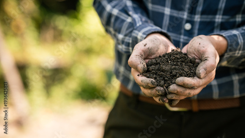 Hands holding rich dark soil outdoors, gardener showing compost in cupped palms