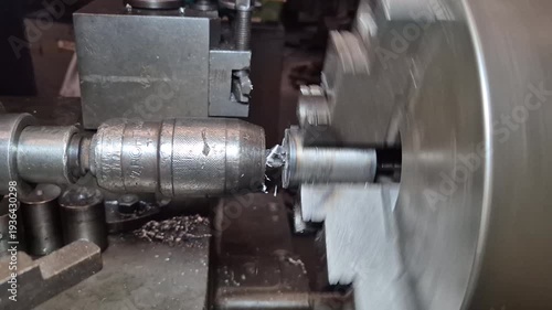 The lathe is rotating to create a workpiece from metal and thread.
