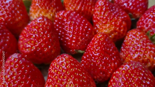Red strawberries are beautifully arranged on a wooden plate.