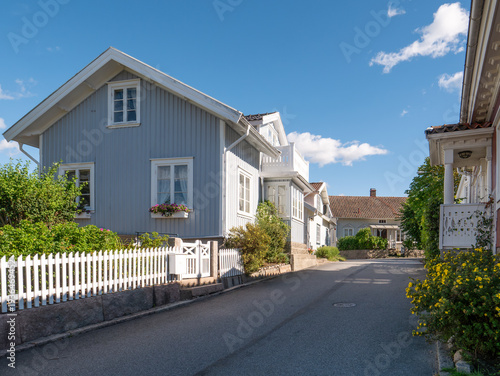 Wooden houses along Postgatan in Grebbestad, Bohuslän, west coast Sweden, with residential streetscene in old town, pastel facades, fences and tiled roofs
