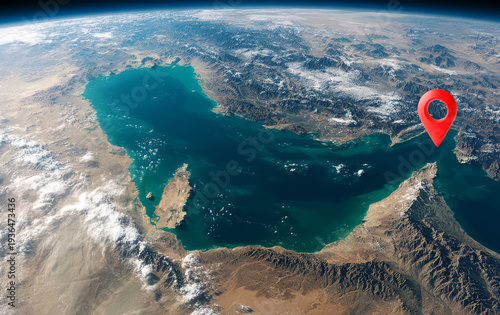 A view of the Strait of Hormuz's coastal area from space, with the location marker highlighted in red.