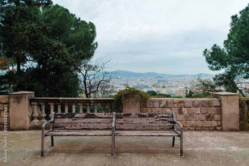 Obraz premium Weathered park bench offers panoramic view of Barcelona cityscape