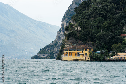 Wallpaper Mural Scenic view of a building on the shore of Riva del Garda, Italy, with mountains in the background. Torontodigital.ca