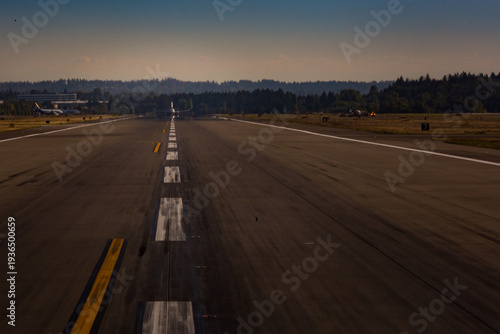 View down an airport runway, an aircraft preparing for take off.
