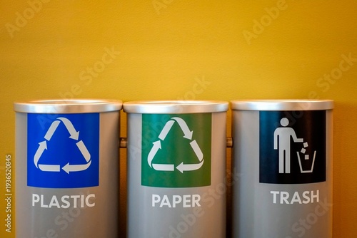 Color-coded bins for plastic recycling, paper recycling, and general trash disposal, promotes sustainability