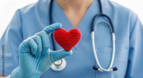 Medical professional in blue gloves holding red knitted heart for cardiology or organ donation