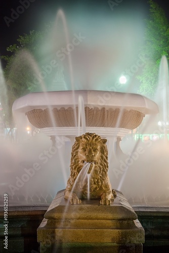 Long exposure night view of the Fountain of the Lions in Plaza Las Delicias, Ponce, Puerto Rico. Water streams from a sculpted lions mouth, surrounded by mist and soft illumination from street lights.