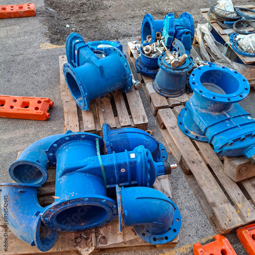 Tableau sur toile Blue ductile iron pipe fittings, flanges and valves stored on wooden pallets at construction site
