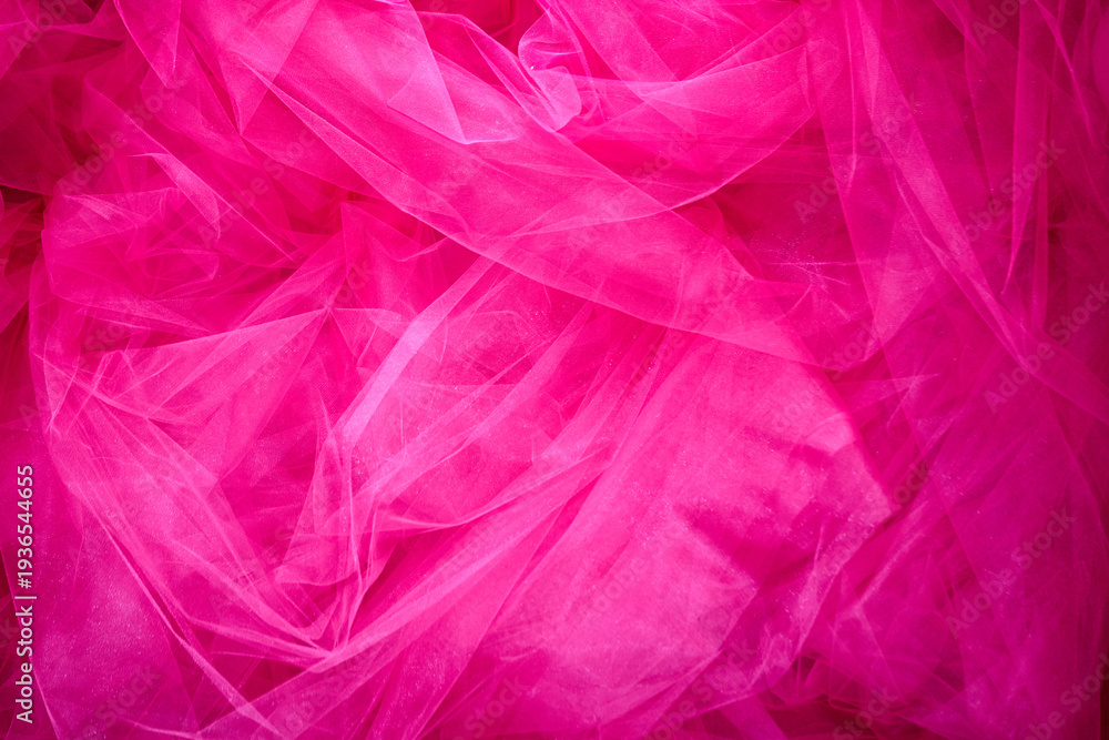 Fototapeta premium Expressive elegance and femininity captured in a vibrant pink tulle background. The delicate folds of lightweight mesh fabric create a rich, dreamy texture perfect for festive designs.