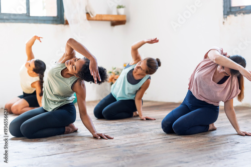 Group of women practicing yoga and stretching indoors in a bright studio