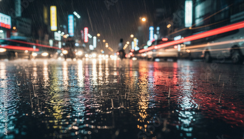 Rain falling on wet city street with colorful light reflections and blurred traffic at night