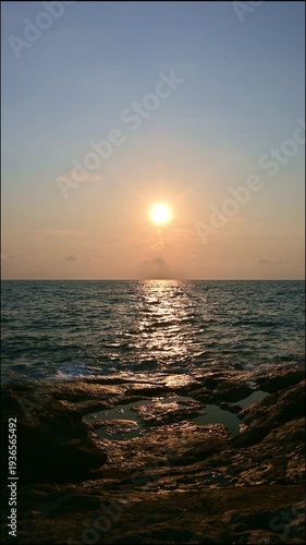 Vertical shot tranquil scene of the sea with waves gently crashing the rocks during sunrise at Koh Samui. Beautiful scenery of coastline under warm sunlight in the morning. Thailand.