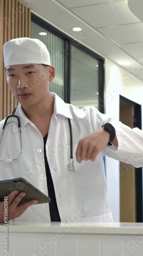 Vertical video: Raising hand, doctor in lab coat calling attention at reception, holding tablet