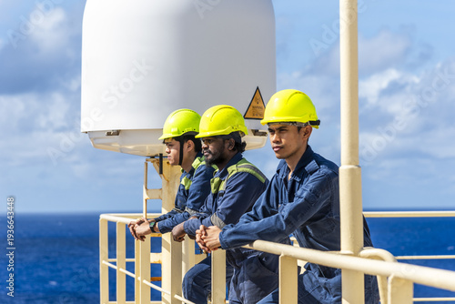 Bild auf Leinwand Maritime professionals standing on the upper deck near satellite equipment, taking a brief pause while at sea