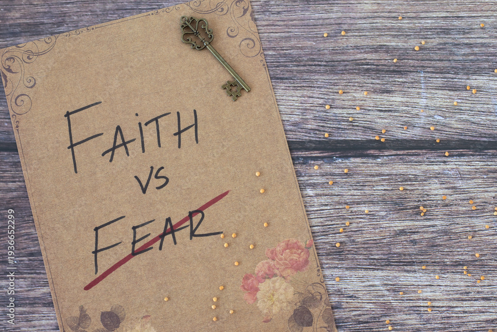 Fototapeta premium Faith vs fear, inspirational quote on rustic paper with mustard seeds and ancient key on wooden background. Belief and trust in God Jesus Christ, biblical concept.