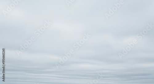A vast expanse of pale gray sky filled with dense, uniform clouds, creating a dreary and overcast natural background texture and atmosphere, copy space, texture, gloomy