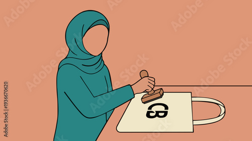 Woman in teal hijab applying stamp on tote bag with SB initial at beige table in a room