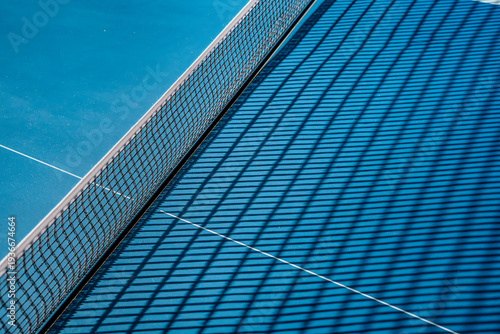 Close-up of the tennis court site. A tennis net that clearly divides the blue playing surface. Perfect for texture or texture, background image