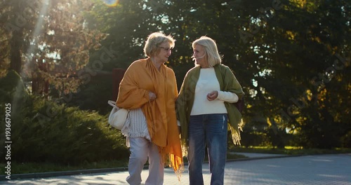 Senior women friends walking together in a park at sunset