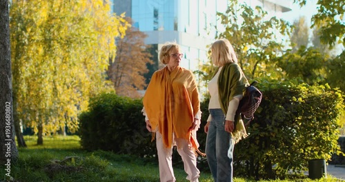 Two senior women friends walking and talking in a beautiful autumn park