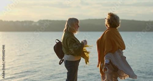 Two senior women friends enjoying the sunset by the lake