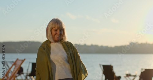 Happy senior woman enjoying a beautiful sunset by the lake