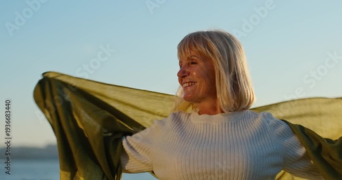 Senior woman enjoying freedom holding a scarf in the wind