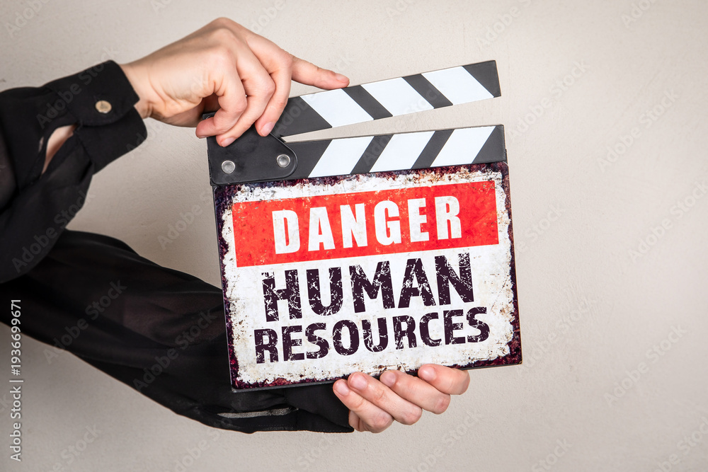 Naklejka premium Danger Human Resources Warning Sign on Film Clapper Board Held in Hands