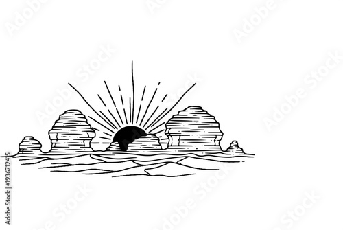 Silhouette of stacked rock formations with a rising sun in the background