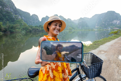 Φωτογραφία Smiling solo traveler holding phone showing selfie