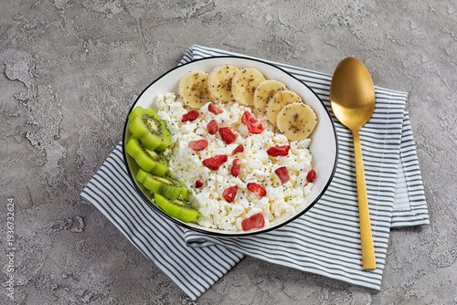Healthy breakfast bowl with cottage cheese, fresh kiwi, banana slices and dried strawberries