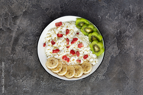 Healthy breakfast bowl with cottage cheese, fresh kiwi, banana slices and dried strawberries
